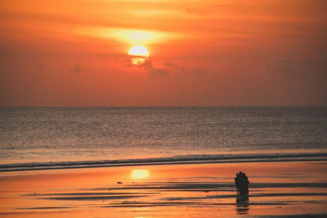 silhouetted people capturing a stunning sunset over kuta beachs vibrant seas 1
